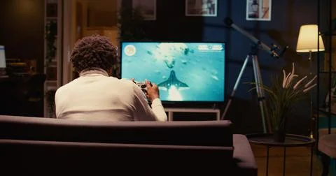 Man in home theatre using cloud gaming service to play demanding science fiction Foto stock