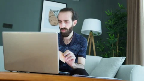 A man at home, upset while holding a credit card and looking at his laptop... Stock Footage 282944636