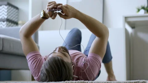 Man at home using phone lying on the floor Stock Footage 102384915