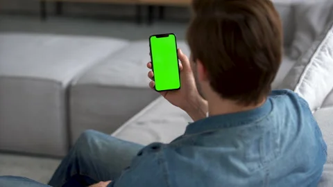 Man at Home using Smartphone with Green Mock-up Screen, Scrolling Gestures Stock Footage 186463930