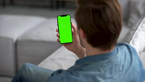 Man at Home using Smartphone with Green Mock-up Screen, Scrolling Gestures Stock Footage 186464148