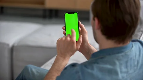 Man at Home using Smartphone with Green Mock-up Screen, Scrolling Gestures Stock Footage 186467348