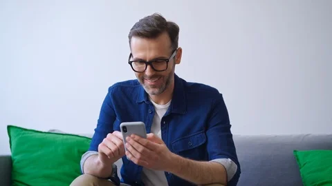 Man at home using smartphone while sitting on couch 動画素材 127122251