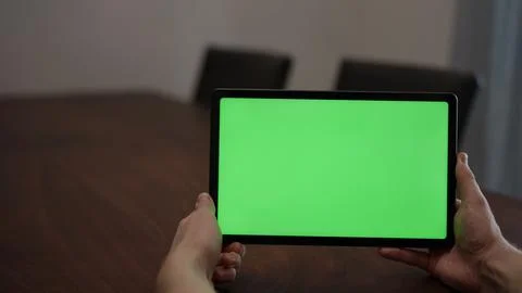 Man at home using tablet pc with green screen while sitting at the table Stock Photos