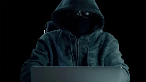Man in hood sitting at table and coding on laptop. Front view close up. Hacker Stock-Footage 82666057