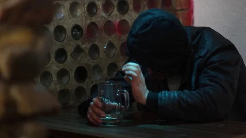 A man in a hood sleeps at the table in the bar Stock Footage 83136490