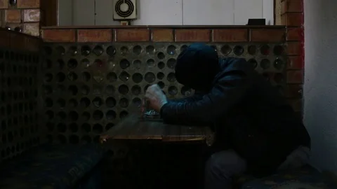 A man in a hood sleeps at the table in the bar2 Stock Footage 83136507