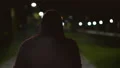 The man in a hood walking and smoking on the night street. slow motion 4k or 4k+ Resolution
