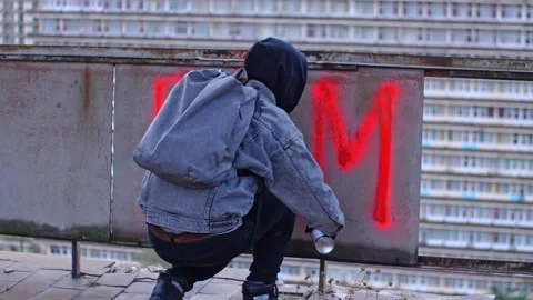 Man in hood writes BLM with spray paint on the wall . Stock Footage 143349653