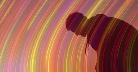 Man in hoodie leaning forward, light arcs sweeping silhouette causing head and Stock Footage 333901360