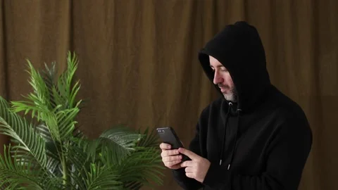 Man in hoodie using smartphone Stock Footage 233623466