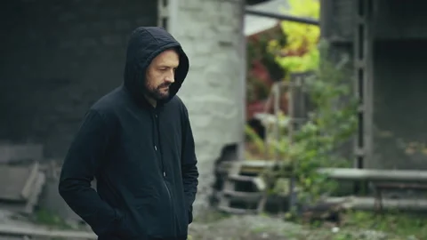 Man in hoodie walking alone through abandoned industrial site, crime concept Stock Footage 337642097