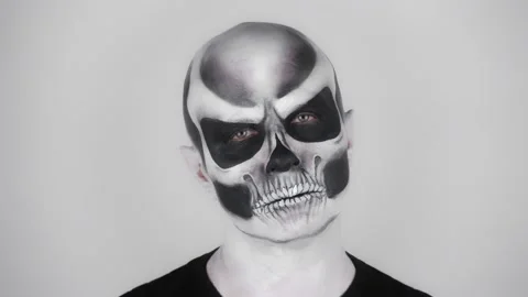 Man in a horrible Halloween skeleton make-up looks at the camera Vídeos de archivo 139290589