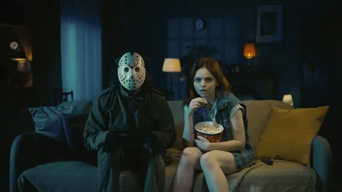 Man horror maniac sitting on the sofa with girl, watching movie, eating popcorn Stock Footage 249993297