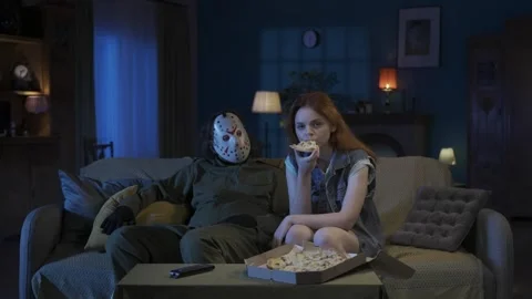 Man horror maniac sitting on the sofa watching tv, girl next to him eating pizza Stock Footage 250005814