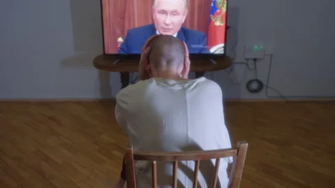 Man in horror watching TV where president Vladimir Putin announces mobilization Stock Footage 214107645