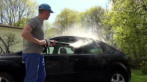 Man, hosing his car at do it yourself car wash, using high pressure water spray 스톡 동영상 64703093