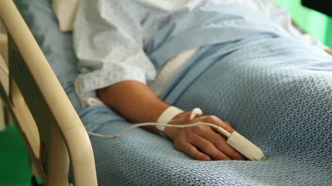 Man in hospital bed - soft focus dolly in on arm/hand - green screen Stock Footage 102391204