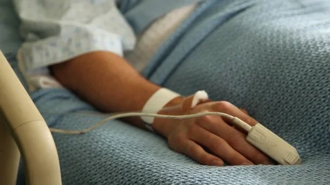 Man in hospital bed - soft focus dolly in close-up on arm/hand - green screen Stock Footage
