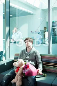 Man In Hospital Waiting Room With Bouquet And Teddy Bear
