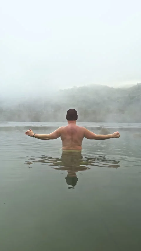 Man in hot spring with arms raised Stock Footage 276331556