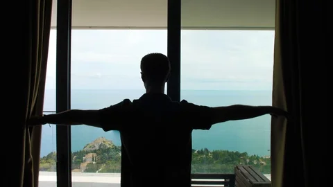 Man in hotel room by the sea, man opens curtains Stock Footage 119281453