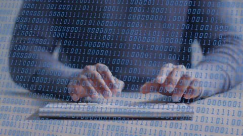 Man hovering before typing on slim keys, binary overlay flowing over hands, Stock Footage 335739597