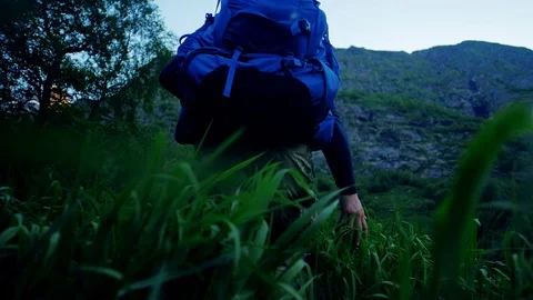 Man with a huge backpack behind him in a hike walks through a field Stock Footage 102652986