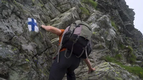 Man with huge backpack climbing mountain wall Stock Footage 138485085