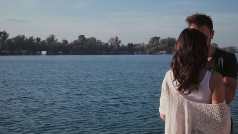 Man hugging and caressing girlfriend by the river on a sunny day Stock Footage 97648445