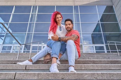 Man hugging his girlfriend while sitting on the stairs outdoors. Foto stock
