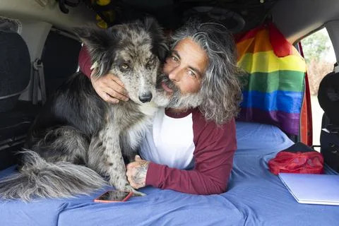 Man hugging his pet inside a mini van Digital nomad lifestyle Stock Photos