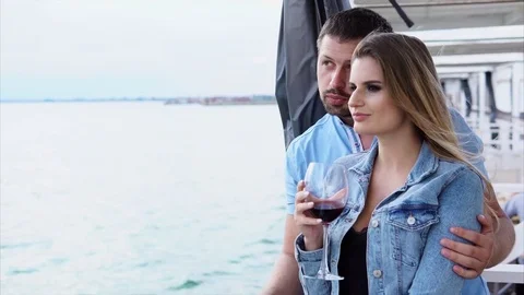 A man hugs a woman who holds a glass of wine in his hand, they ride a boat Stock Footage
