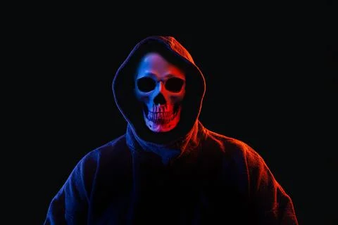 Man with human skull instead of face in dark hoodie illuminated Foto stock
