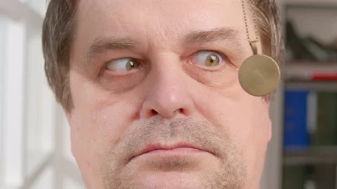 Man in hypnosis session, hypnotic pendant on chain swinging in front Stock Footage 189214779