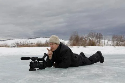 Man on ice with video camera pointing Stock Photos