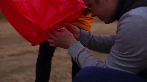 Man igniting the candle in sky lantern. Launching of the sky lantern. Stock Footage 76850929