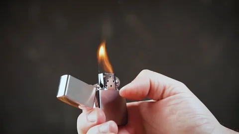 Man is igniting chrome lighter with windproof in hand. 動画素材 100194806