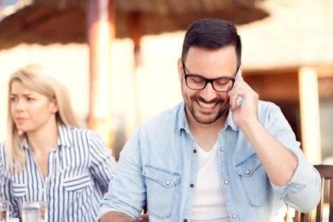 Man ignoring his girlfriend while talking on the phone Stock Photos