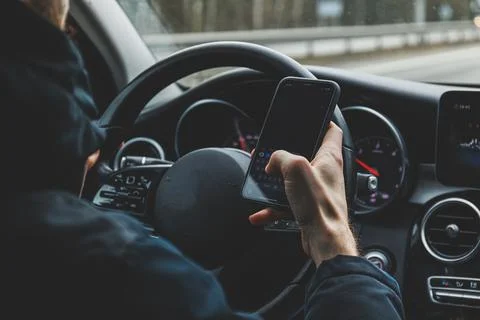 Man ignoring safety and using mobile phone while driving car Stock Photos