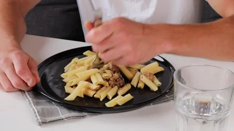 A man impales feather pasta on a fork as he eats. Stock Footage 281148885
