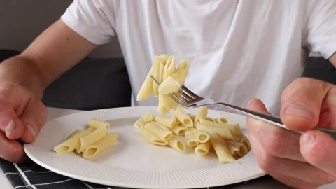 A man impales feather pasta on a fork as he eats Stock Footage 281148902