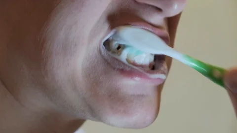 A man incorrectly brushes his teeth with a toothbrush Stock Footage 122818929