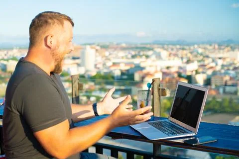 Man indignant working on a computer in a cafe with a beautiful view Stock Photos