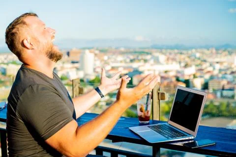 Man indignant working on a computer in a cafe with a beautiful view Stock Photos