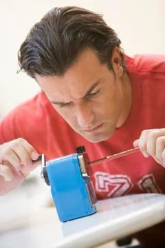 Man indoors using pencil sharpener Stock-Fotos