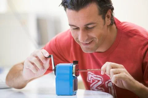 Man indoors using pencil sharpener smiling Stock-Fotos