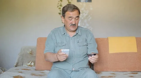 Man indoors using smart phone and credit card purchase fee Video stock 65374254