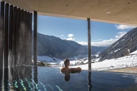 Man in infinity edge pool with Dolomites view and modern roof Stock Photos