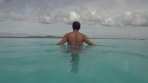 Man in Infinity Pool Overlooking the Ocean Shot in Slow Motion Stock Footage 78760554
